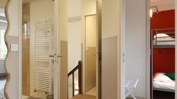 Une pièce avec un lit superposé, un radiateur, une porte et un couloir.