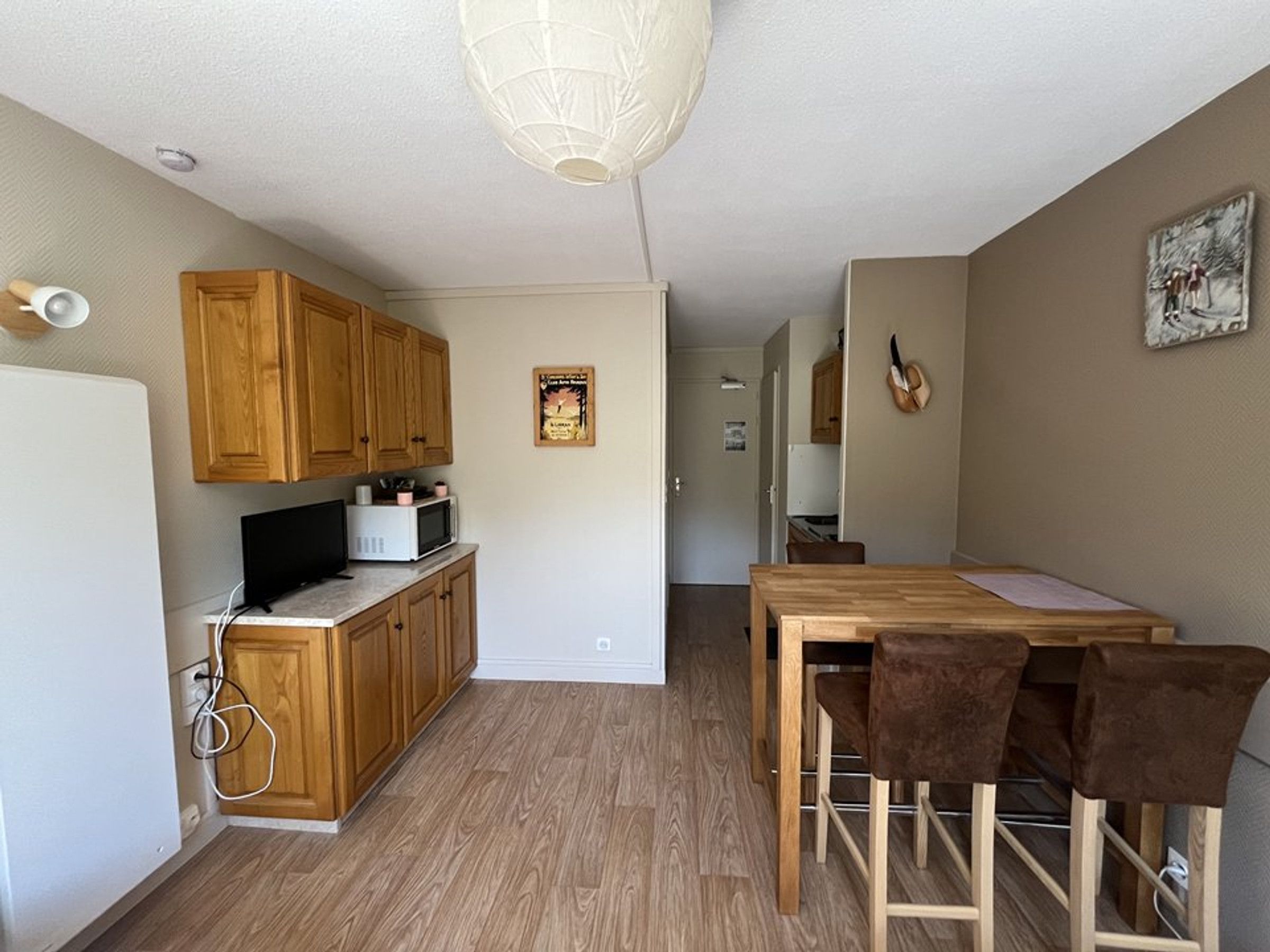 A compact kitchen with wooden cabinets, a microwave, and a dining area with a table and chairs.
