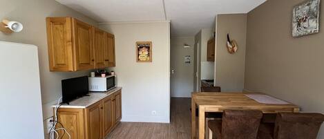 A compact kitchen with wooden cabinets, a microwave, and a dining area with a table and chairs.