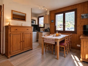 A wooden interior with a dining table, chairs, a kitchen area, and a television. - Quiet studio with parking - 4 guests (Le Grand-Bornand)