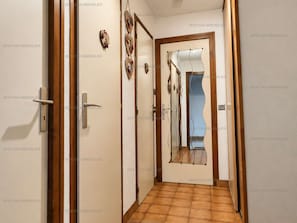 A hallway with a tiled floor, wooden doors, and a mirror on the wall. - Quiet studio with parking - 4 guests (Le Grand-Bornand)