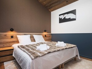 Ein Schlafzimmer mit einem hölzernen Kopfende, einem Bett mit weißer Bettwäsche, einem Fellüberwurf und einem Wandbild eines Eisbären.