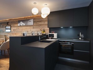 Eine moderne Küche mit einer zentralen Kochinsel, integrierten Geräten und einer Wand als Holzdekor.
