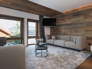 Ein modernes Wohnzimmer mit einer Couch, einem Couchtisch und einem an einer Holzwand montierten Fernseher.