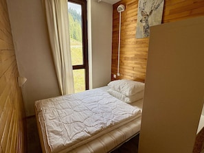 A bedroom with a bed, a window with curtains, a wall-mounted lamp, and a painting. - Apartment mountain view - 4 guests (Plagne Bellecôte)