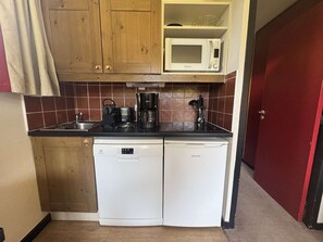 A compact kitchen with wooden cabinets, a microwave, a coffee maker, and a dishwasher. - Apartment mountain view in Belle Plagne - 4 guests (Belle Plagne)