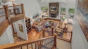 A spacious living area with a fireplace, a staircase, and a view of the outdoors. - Mountain Retreat + Pet Friendly + Game Room + Community Hot Tub | Wild Iris Lodg (Edwards)
