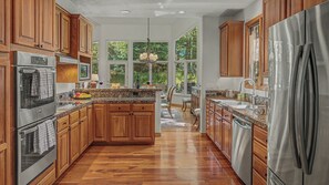 A kitchen with wooden cabinets, stainless steel appliances, and a large island. - Mountain Retreat + Pet Friendly + Game Room + Community Hot Tub | Wild Iris Lodg (Edwards)