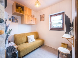 Ein gemütliches Zimmer mit einer Couch, einem kleinen Tisch, einem Fernseher und einem Fenster mit Blick.