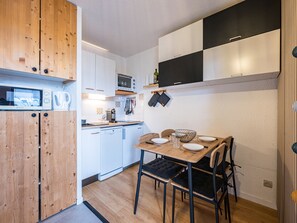 A compact kitchen with wooden cabinets, a microwave, a coffee maker, and a dining table with chairs. - Modern studio, piste view - 4 guests (La Toussuire)