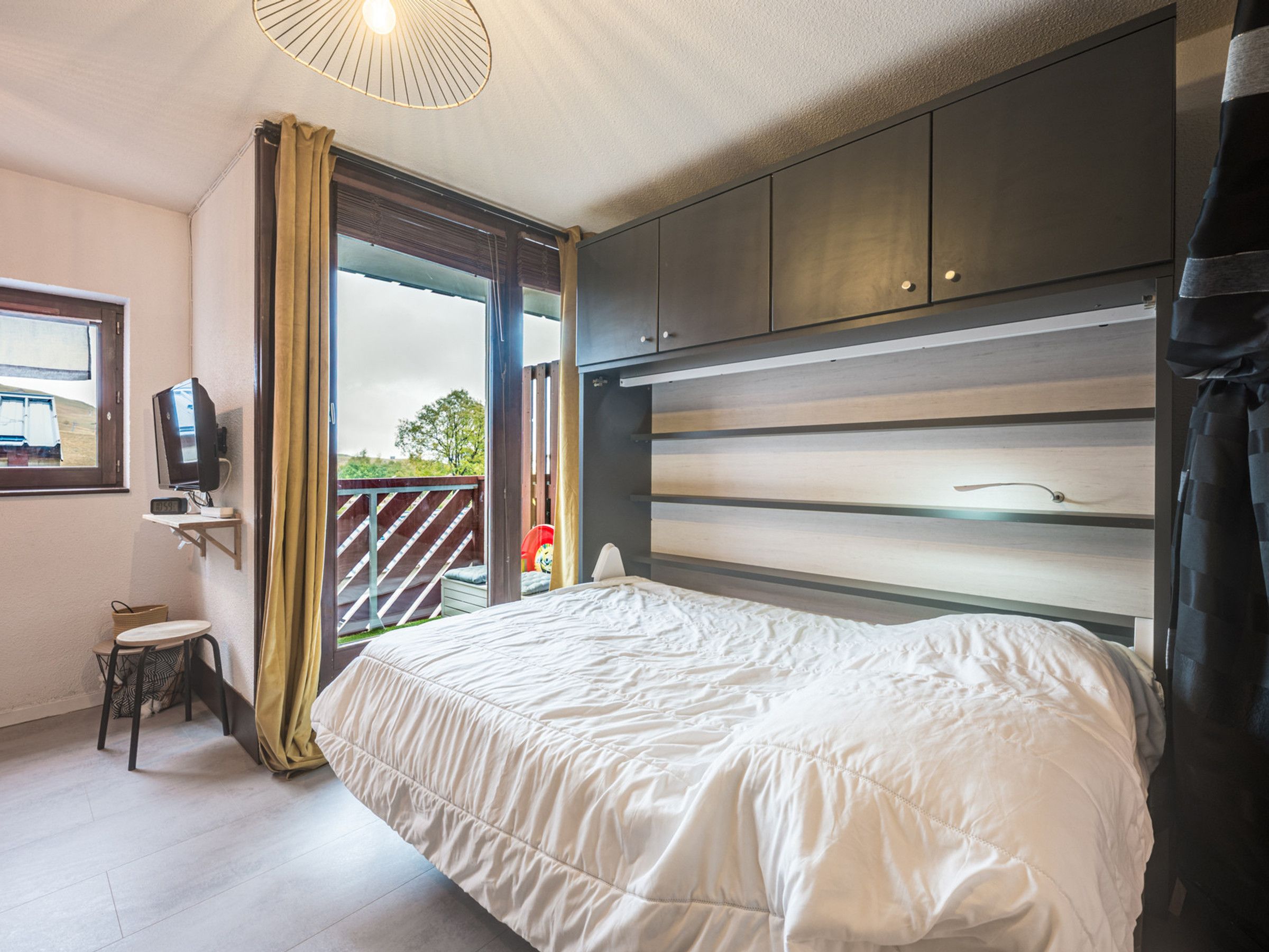 Une chambre à coucher avec un lit, une télévision, une fenêtre et une vue sur l’extérieur.