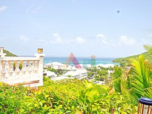 A coastal view with a building in the foreground, a clear sky, and a distant view of the sea. - Villa panoramic sea view - 12 guests (Saint-Martin)