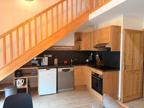 A compact kitchen with wooden cabinets, a dishwasher, a stove, and a wooden staircase. - Lovely apartment near slopes - 5 guests (Pralognan-la-Vanoise)