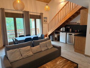 A modern living room with a sofa, dining table, and kitchen area with a staircase. - Lovely apartment near slopes - 5 guests (Pralognan-la-Vanoise)