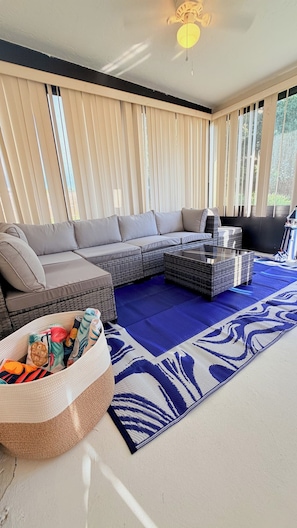 Un salon moderne avec un canapé d’angle, une table basse en verre et un tapis à motifs.