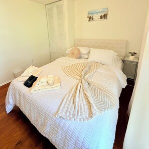 Ein ordentlich gemachtes Bett mit einer gestreiften Decke, einem gefalteten Handtuch und einem schwarzen Gegenstand mit der Aufschrift 'Motel'.