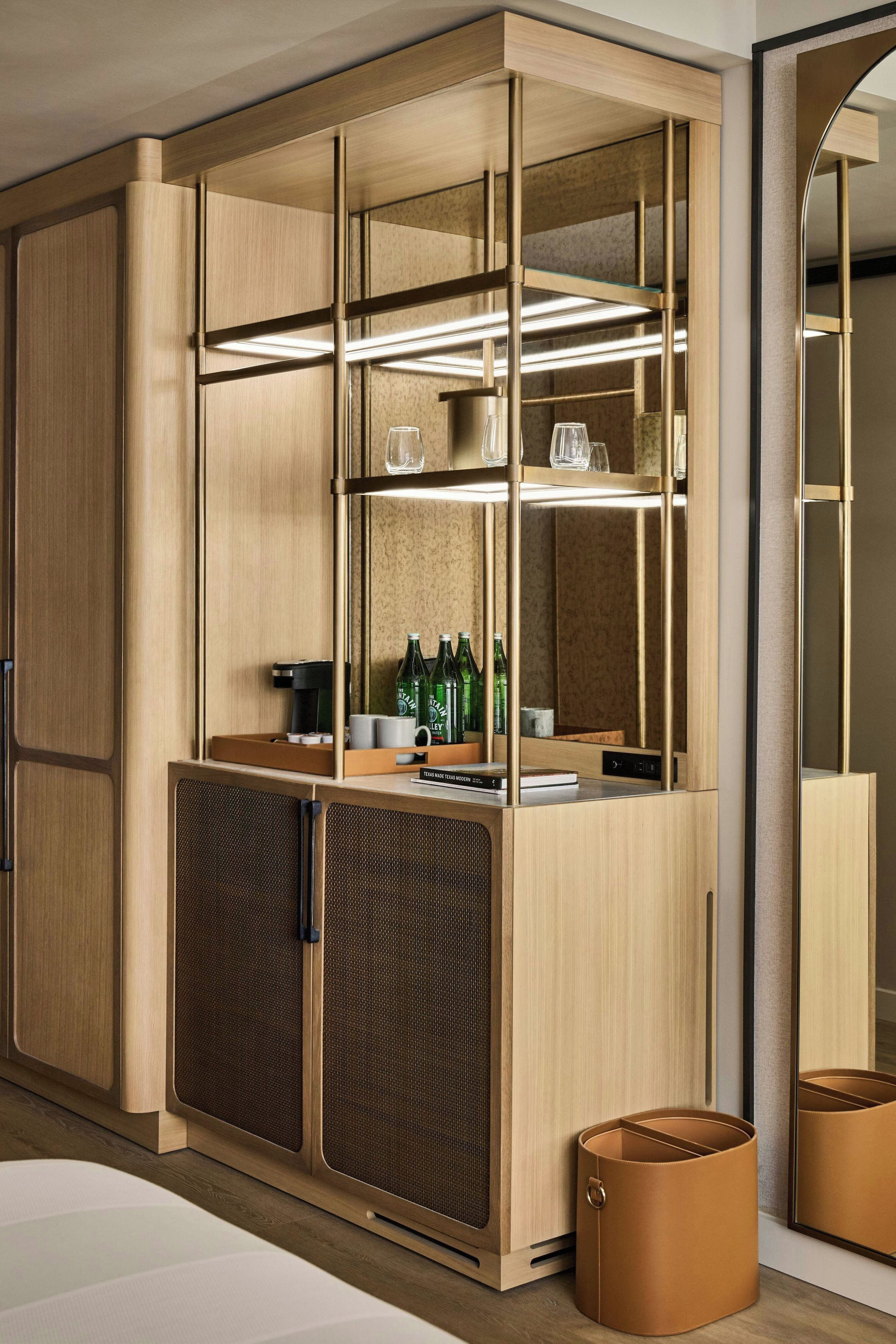 A modern kitchenette with built-in appliances, a glass-fronted storage unit, and a coffee machine.