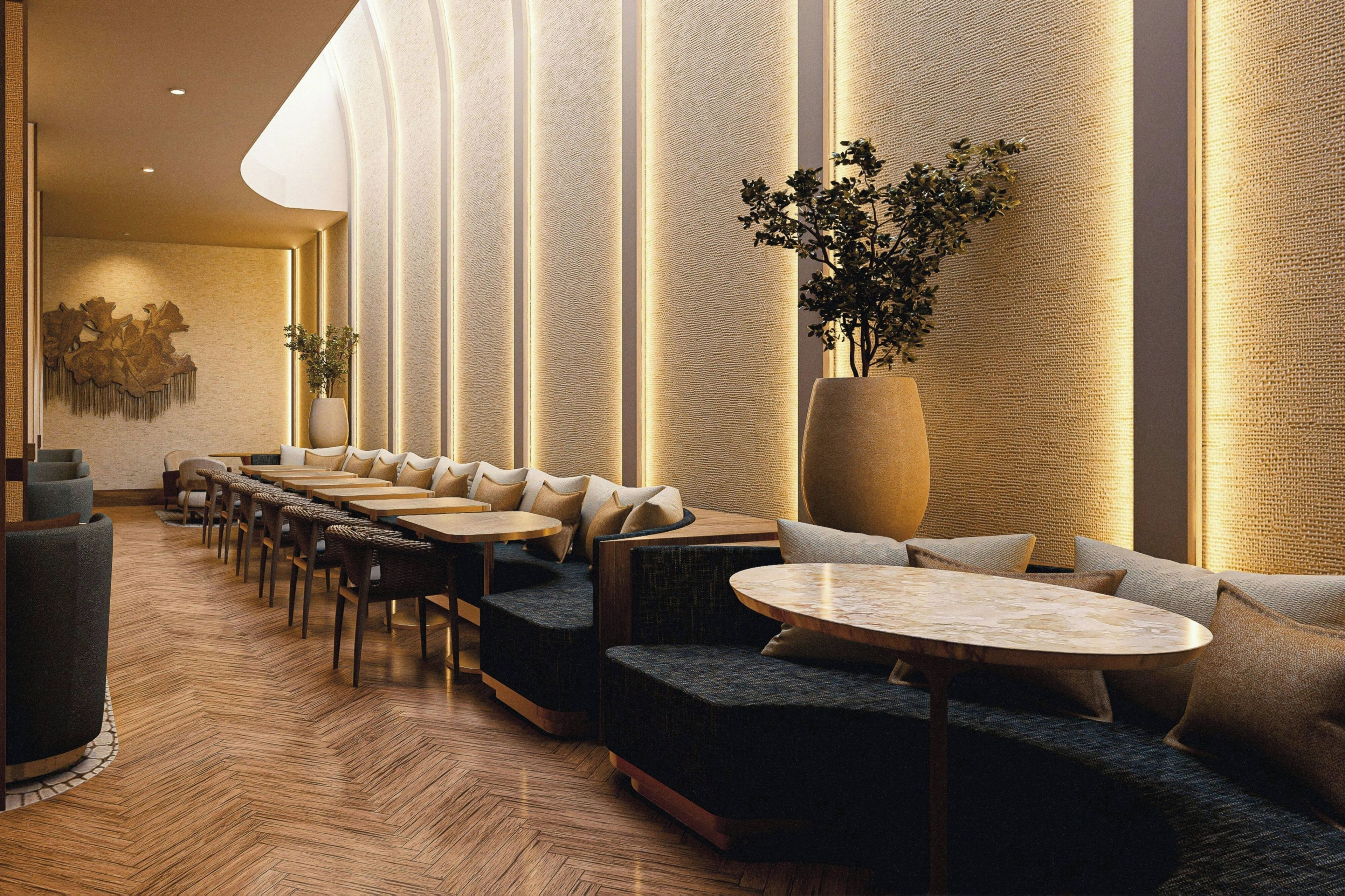A modern lounge area with sofas, tables, and a large plant.