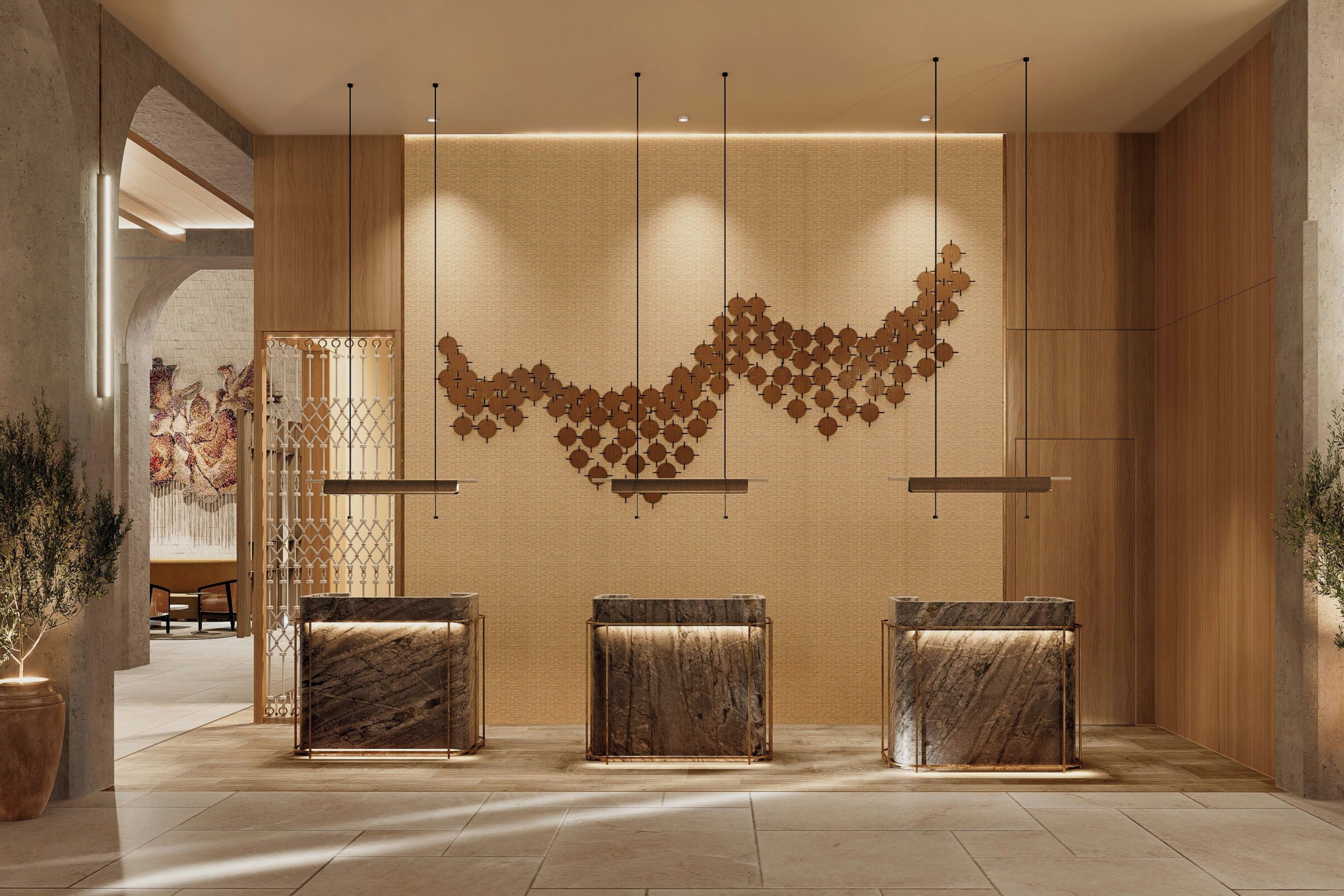 Un área de recepción moderna con mostradores de mármol, un diseño de pared texturizado e iluminación colgante.