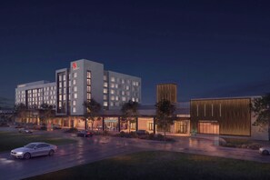 A modern hotel with multiple floors, a conference center, and a well-lit outdoor area.