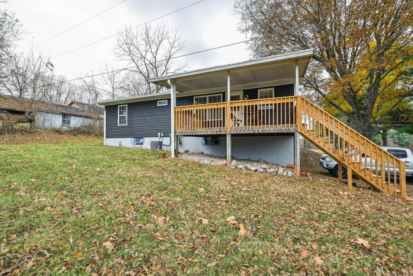 A two-story house with a wooden deck and a staircase leading to the upper level.