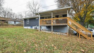A two-story house with a wooden deck and a staircase leading to the upper level.