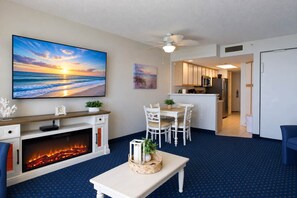 A living room with a fireplace, a dining area, and a kitchen in the background. - Bay Watch Resort 1519 (North Myrtle Beach)