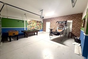 Ein Zimmer mit Billardtisch, Kicker und Trampolin.