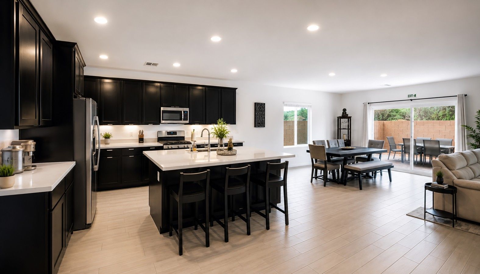 A modern kitchen with a central island, dining area with a table and chairs, and a seating area with a sofa.