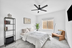 Ein Schlafzimmer mit einem Bett, einem Bücherregal, einem Globus als Wandkunst, einem Fenster und einem Deckenventilator.