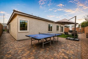 A brick patio with a ping pong table, a barbecue grill, and a covered seating area. - Modern 4BR · 10 Min to Strip, 8 Min to Airport (Las Vegas)
