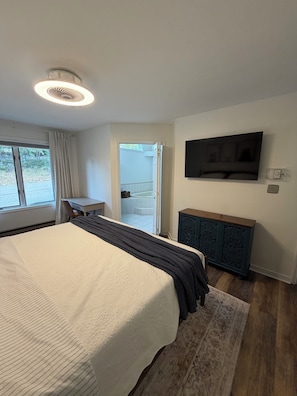 Ein Hotelzimmer mit einem großen Bett, einem Schreibtisch, einem Fernseher und Blick ins Freie.