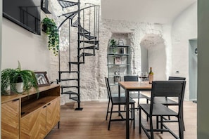 A modern interior with a spiral staircase, wooden furniture, and a rustic stone wall. - SW Roman Holiday Apartment with Private Terrace in Monti (Roma)