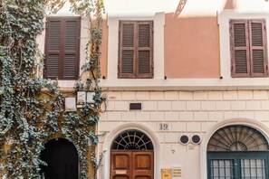 Un immeuble avec une porte marron, une plaque portant le numéro « 19 », et une porte verte.