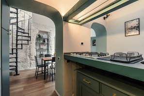 Eine moderne Küche mit Einbauherd, ein Essbereich mit Tisch und Stühlen sowie eine Wendeltreppe, die zu einer oberen Ebene führt.