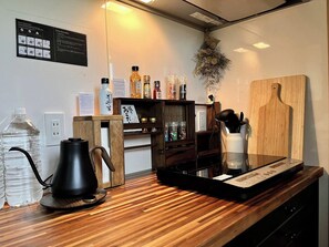Una cucina moderna con un piano di lavoro in legno, un bollitore, una bottiglia d'acqua e diversi utensili da cucina.
