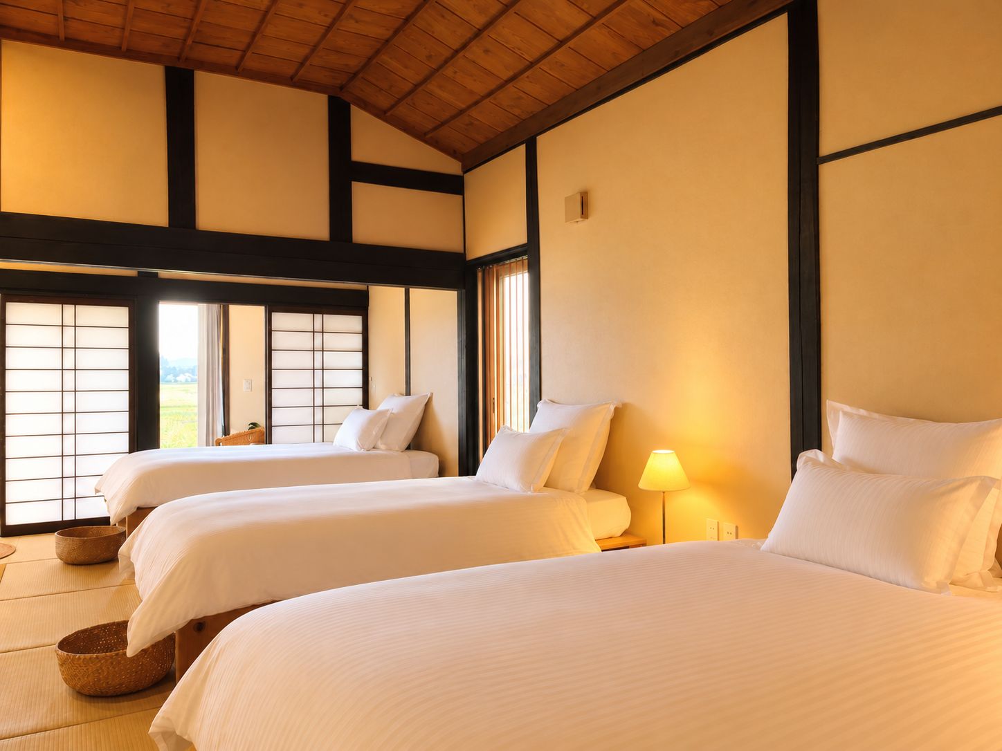 A traditional Japanese-style room with tatami flooring, two beds with white bedding, and a view through shoji screens.