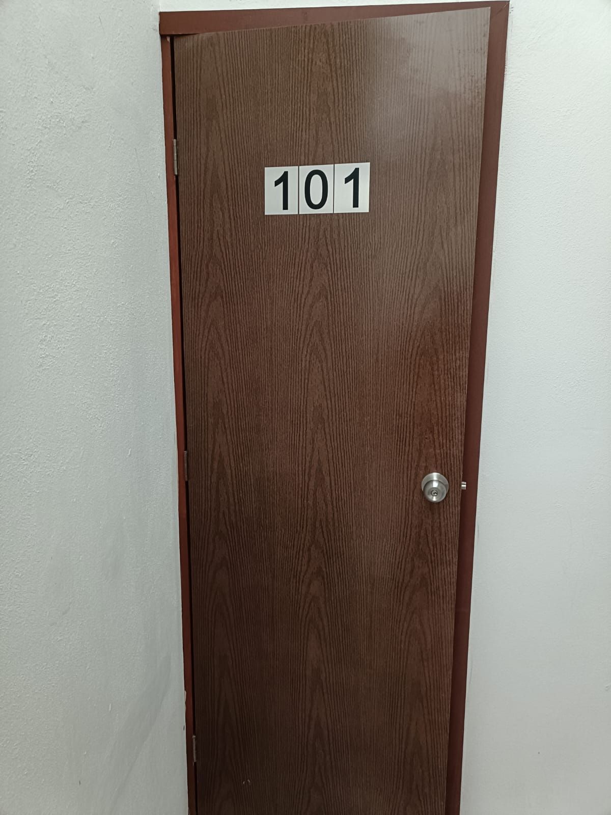 A brown door with a number '101' sign on it.