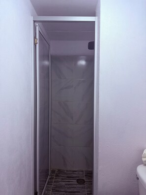 A narrow, enclosed space with a tiled floor and a door with a metal handle.