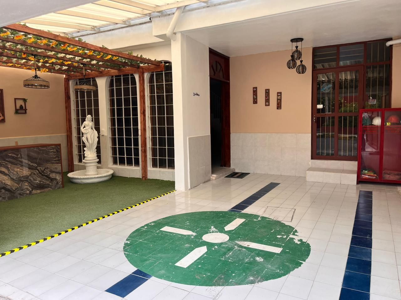 A hotel lobby with a fountain, a statue, and a green circular design on the floor.
