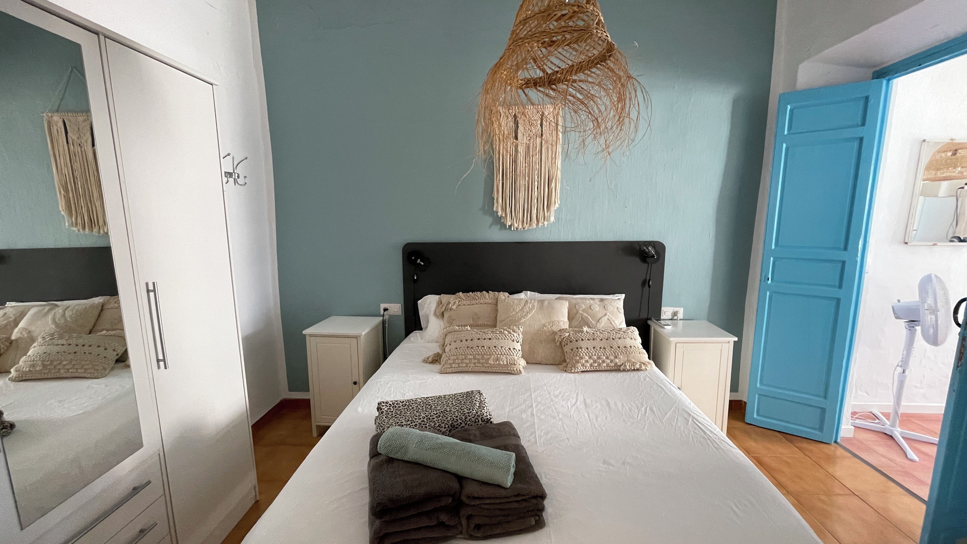 A bedroom with a bed, nightstands, a wardrobe, and a blue door.