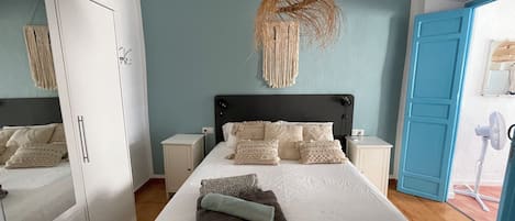 A bedroom with a bed, nightstands, a wardrobe, and a blue door.