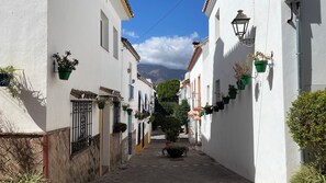 A narrow street with white buildings, potted plants, and a clear sky. - Charming apartment in Estepona old town (Estepona)