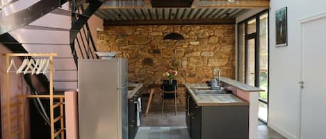 A modern kitchen with a stone wall, a built-in island, and a staircase.