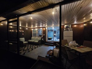 Ein Zimmer mit einer Glastrennwand, einem Sofa, einem Tisch und einem durch die Trennwand einsehbarer Küchenbereich.