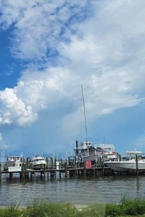 A marina with boats docked at wooden piers under a partly cloudy sky. - Mane Wave's Space Coast Retreat (Cocoa)