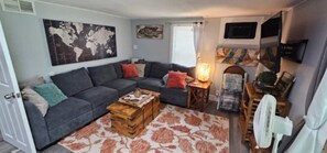 Ein Wohnzimmer mit einer Couch, einem Couchtisch, einer Lampe und einem Ventilator.