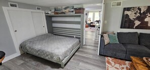 Ein Schlafzimmer mit einem Bett, einem grauen Sofa und einer Weltkarte an der Wand.