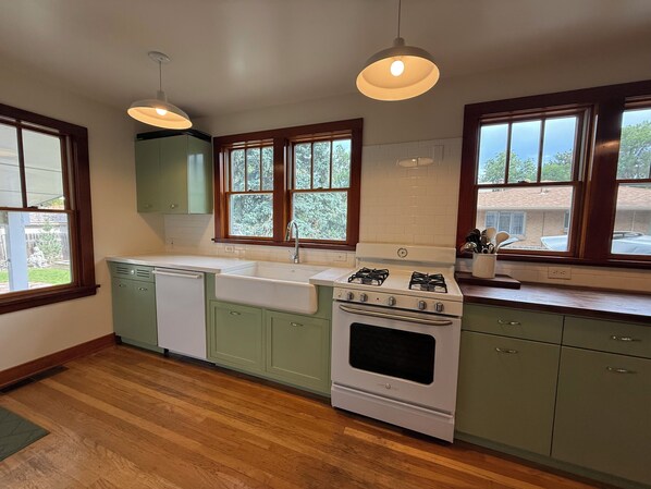 A kitchen with a white stove, green cabinets, and wooden flooring.