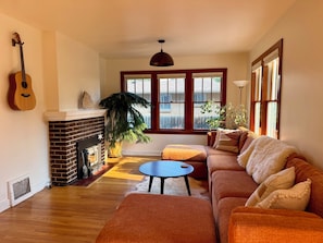A living room with a fireplace, a sofa set, a coffee table, and a guitar.